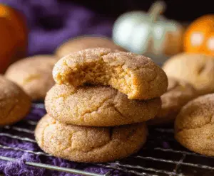Creamy Pumpkin Snickerdoodle Cookies topped with cinnamon sugar on a rustic wooden surface, perfect for fall baking and holiday treats.