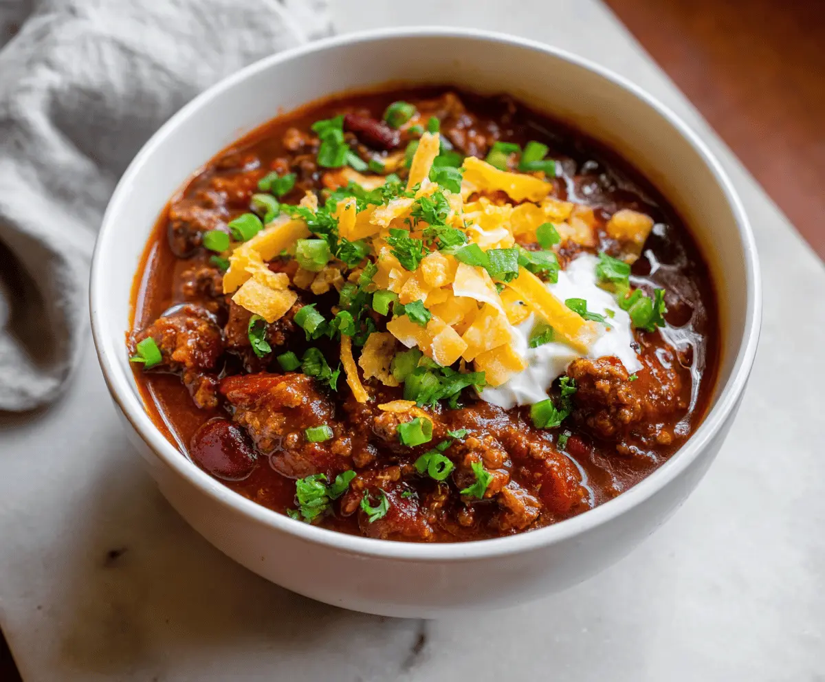 Delicious homemade Taco Chili served in a bowl with ground beef, beans, tomatoes, and spices, garnished with fresh cilantro and shredded cheese