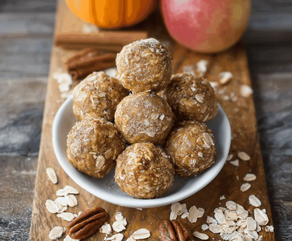 Healthy apple cinnamon pumpkin protein balls on a white plate with a rustic background, perfect for a nutritious snack or energy bite