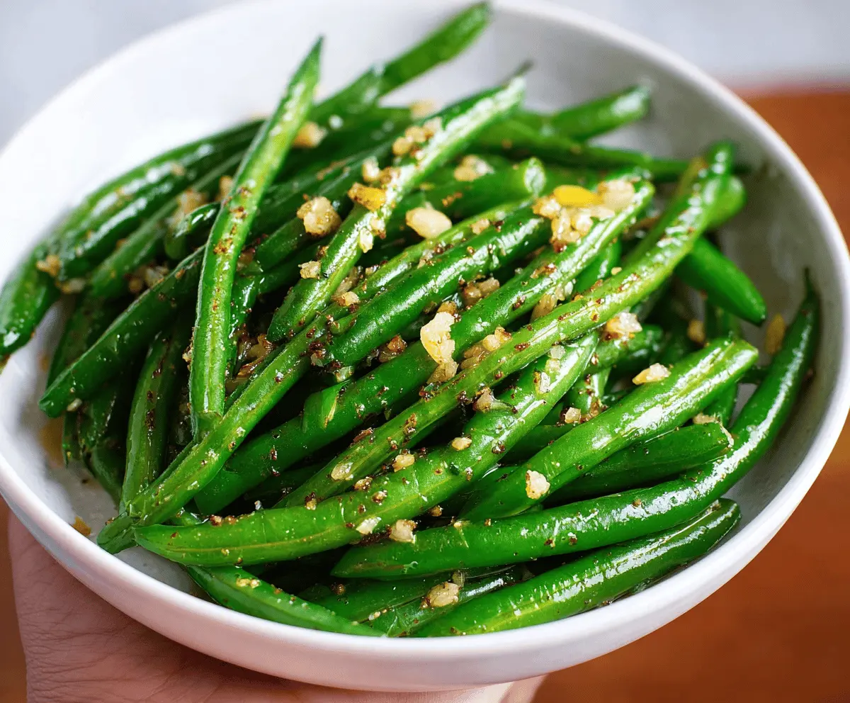 Delicious Garlic Butter Green Beans served on a plate with fresh herbs for a flavorful side dish.