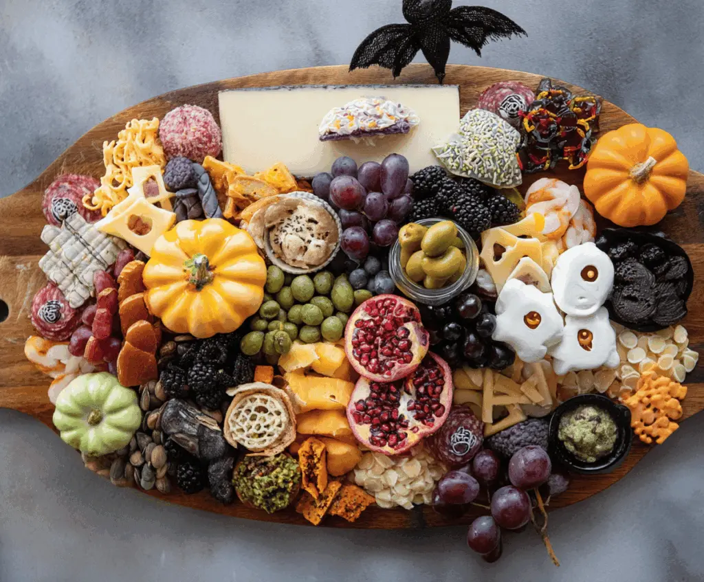 Colorful Halloween-themed charcuterie board featuring spooky-shaped cheeses, assorted cured meats, fresh fruits, Halloween-themed crackers, and decorative edible accents perfect for a festive party platter.