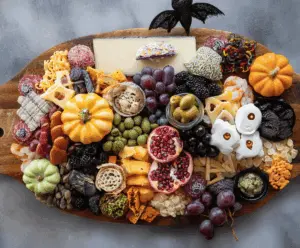 Colorful Halloween-themed charcuterie board featuring spooky-shaped cheeses, assorted cured meats, fresh fruits, Halloween-themed crackers, and decorative edible accents perfect for a festive party platter.