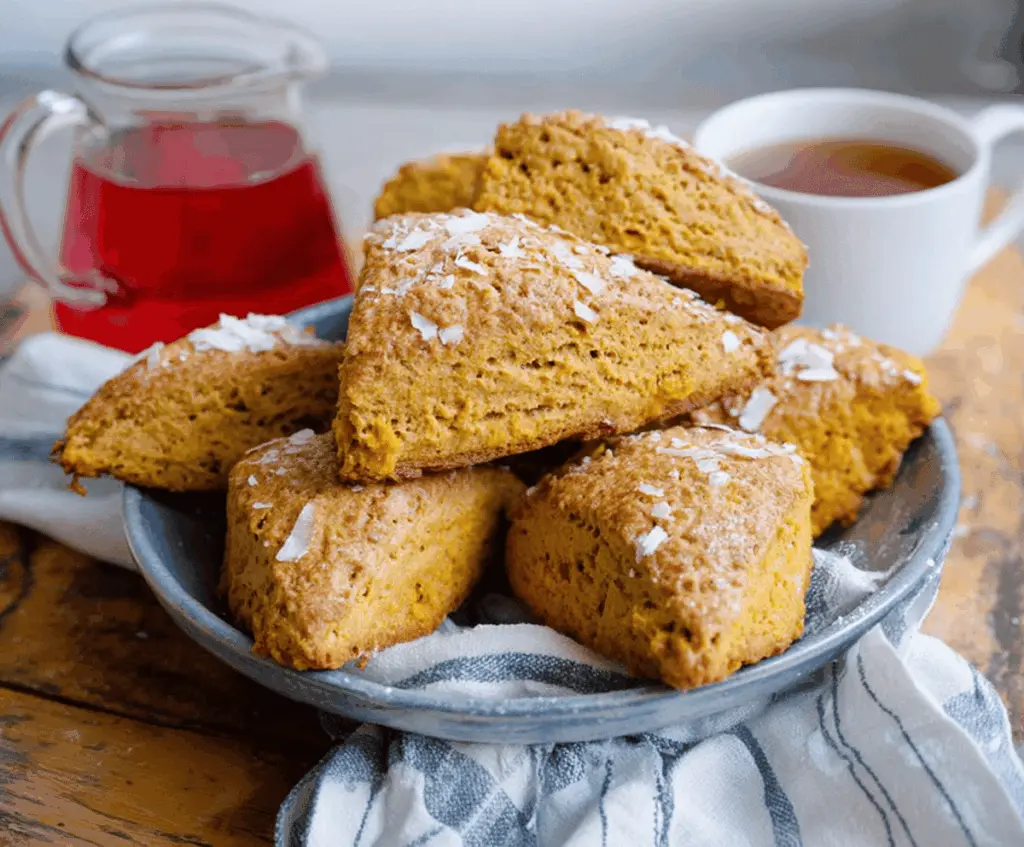 Delicious golden-brown sweet potato scones on a rustic plate, garnished with a sprig of fresh herbs, perfect for breakfast or tea time
