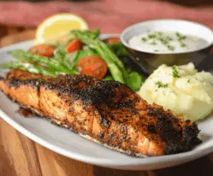 Delicious grilled Texas Roadhouse Salmon fillet served with fresh lemon wedges and vibrant vegetables on a white plate