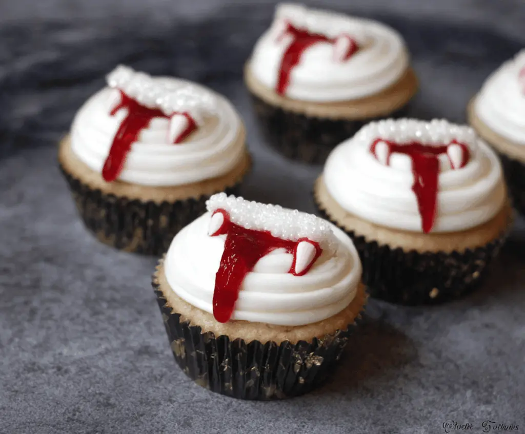 Vampire Bite Cupcakes with red raspberry filling, topped with black and red themed icing, perfect for Halloween treats