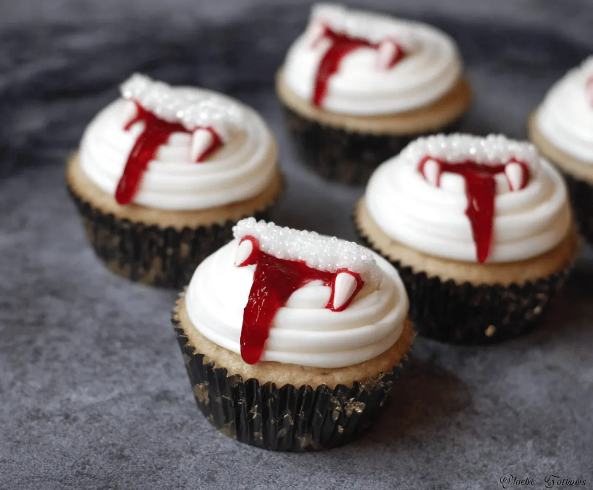 Vampire Bite Cupcakes with red raspberry filling, topped with black and red themed icing, perfect for Halloween treats