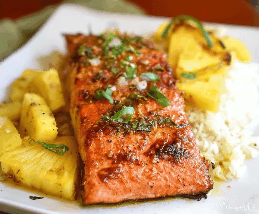 Delicious Honey Pineapple Salmon served on a white plate with fresh pineapple slices and a drizzle of honey glaze.