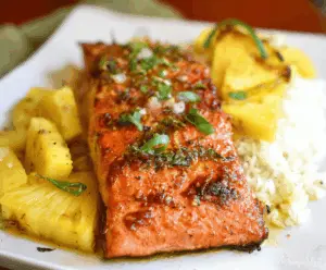 Delicious Honey Pineapple Salmon served on a white plate with fresh pineapple slices and a drizzle of honey glaze.