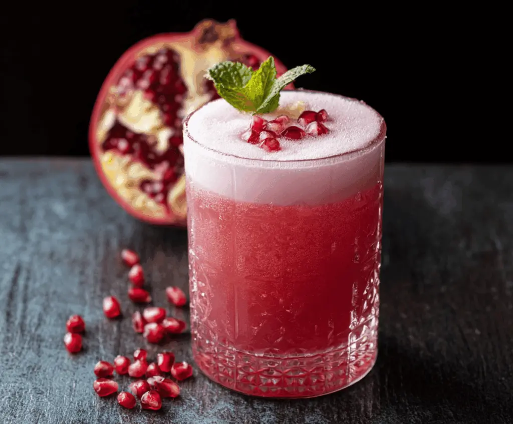 Refreshing Pomegranate Gin Fizz in a cocktail glass with pomegranate seeds and mint garnish.