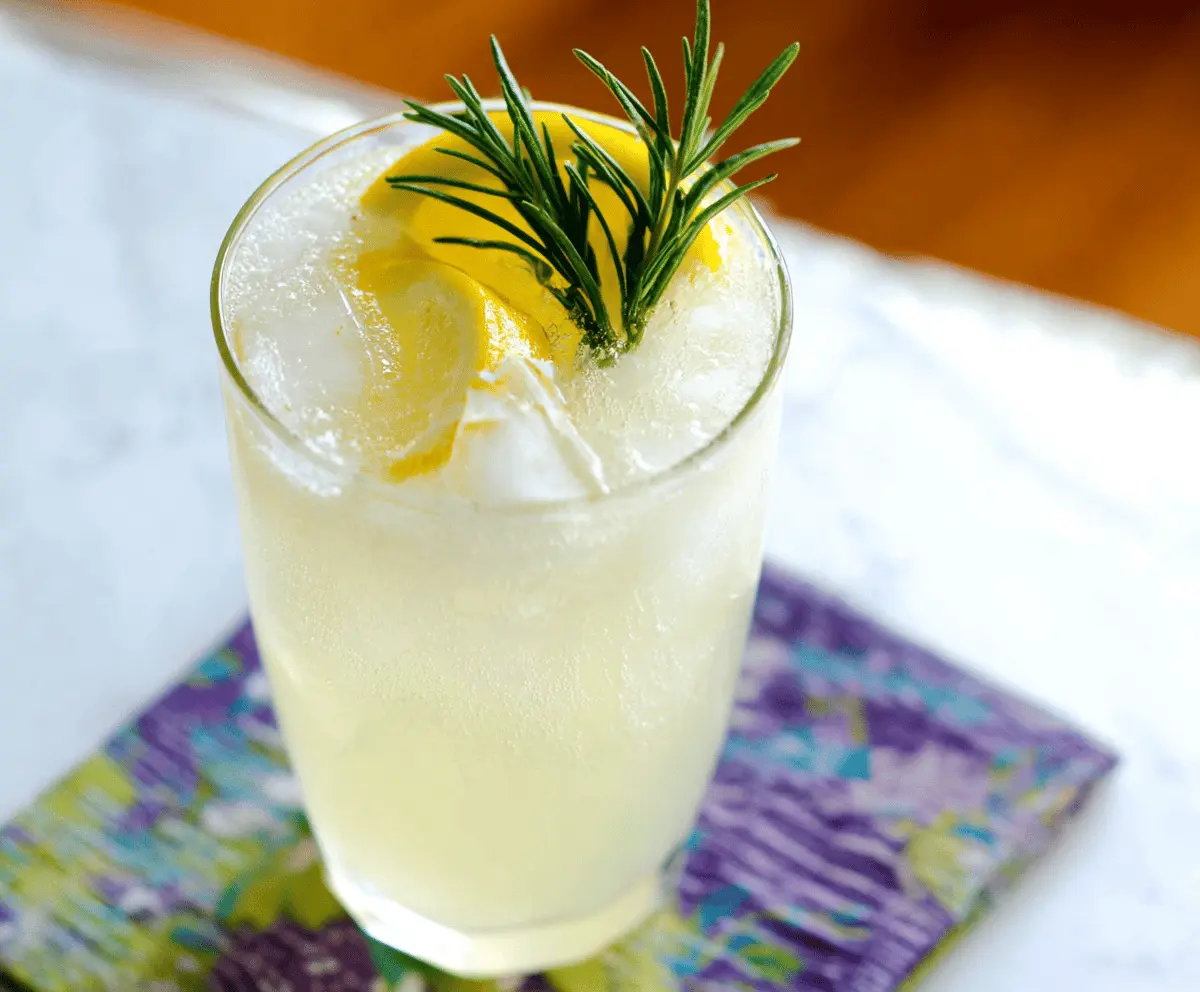 Refreshing Rosemary Gin Fizz cocktail garnished with fresh rosemary and lemon slice.