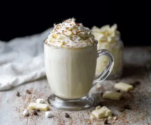 Creamy white hot chocolate in a mug with whipped cream and sprinkles, perfect for winter comfort.