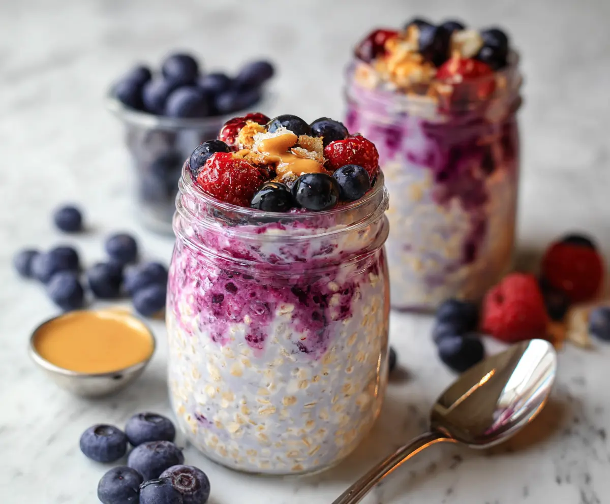 Creamy Berry Cheesecake Overnight Oats topped with fresh mixed berries and a drizzle of honey