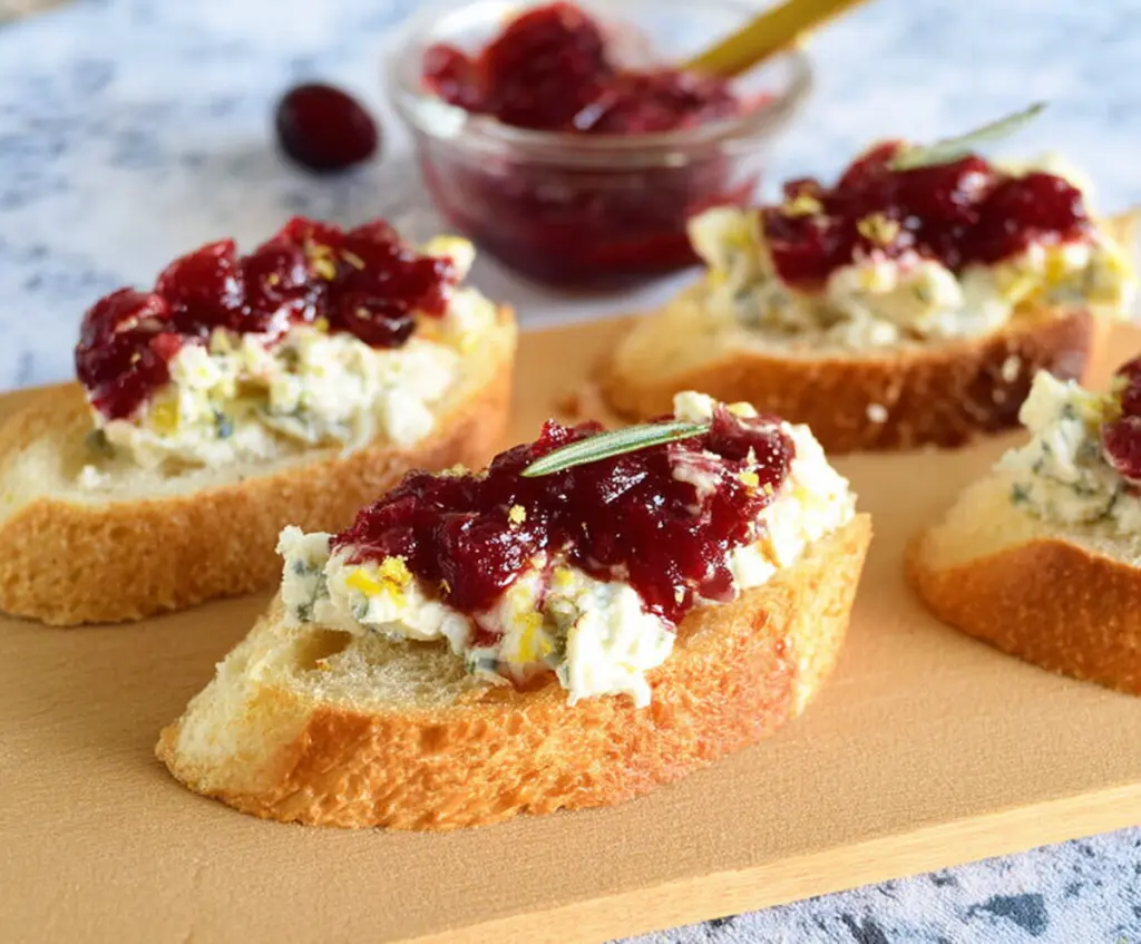 Delicious Blue Cheese Cranberry Crostini served on a rustic wooden platter, showcasing creamy blue cheese topped with vibrant cranberries.
