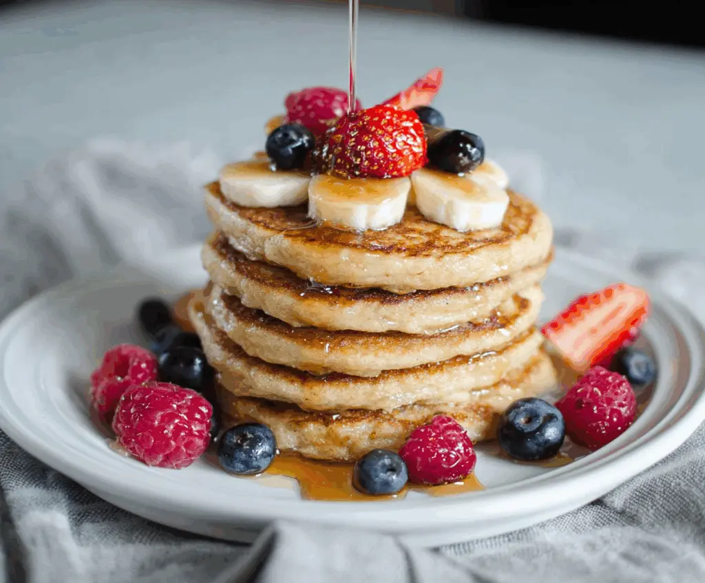 Delicious cottage cheese protein pancakes topped with fresh berries and maple syrup.