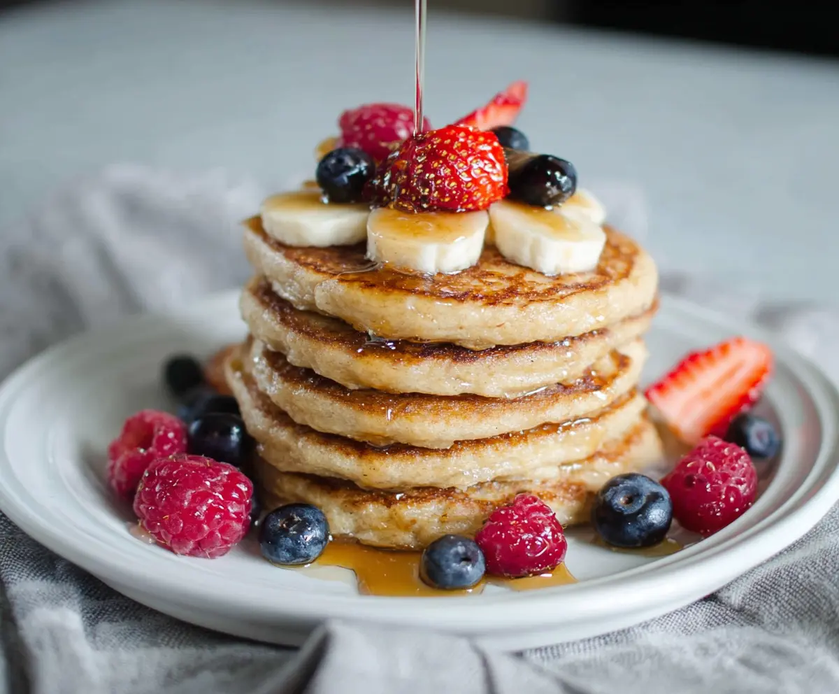 Delicious cottage cheese protein pancakes topped with fresh berries and maple syrup.