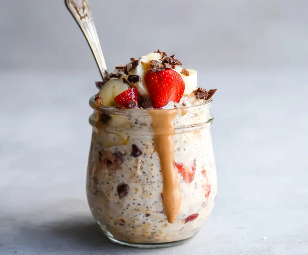 Delicious Banana Split Overnight Oats topped with fresh bananas, strawberries, and a cherry for a healthy breakfast.