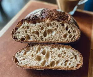 Freshly baked crust sourdough bread served with a cup of coffee on a rustic table.