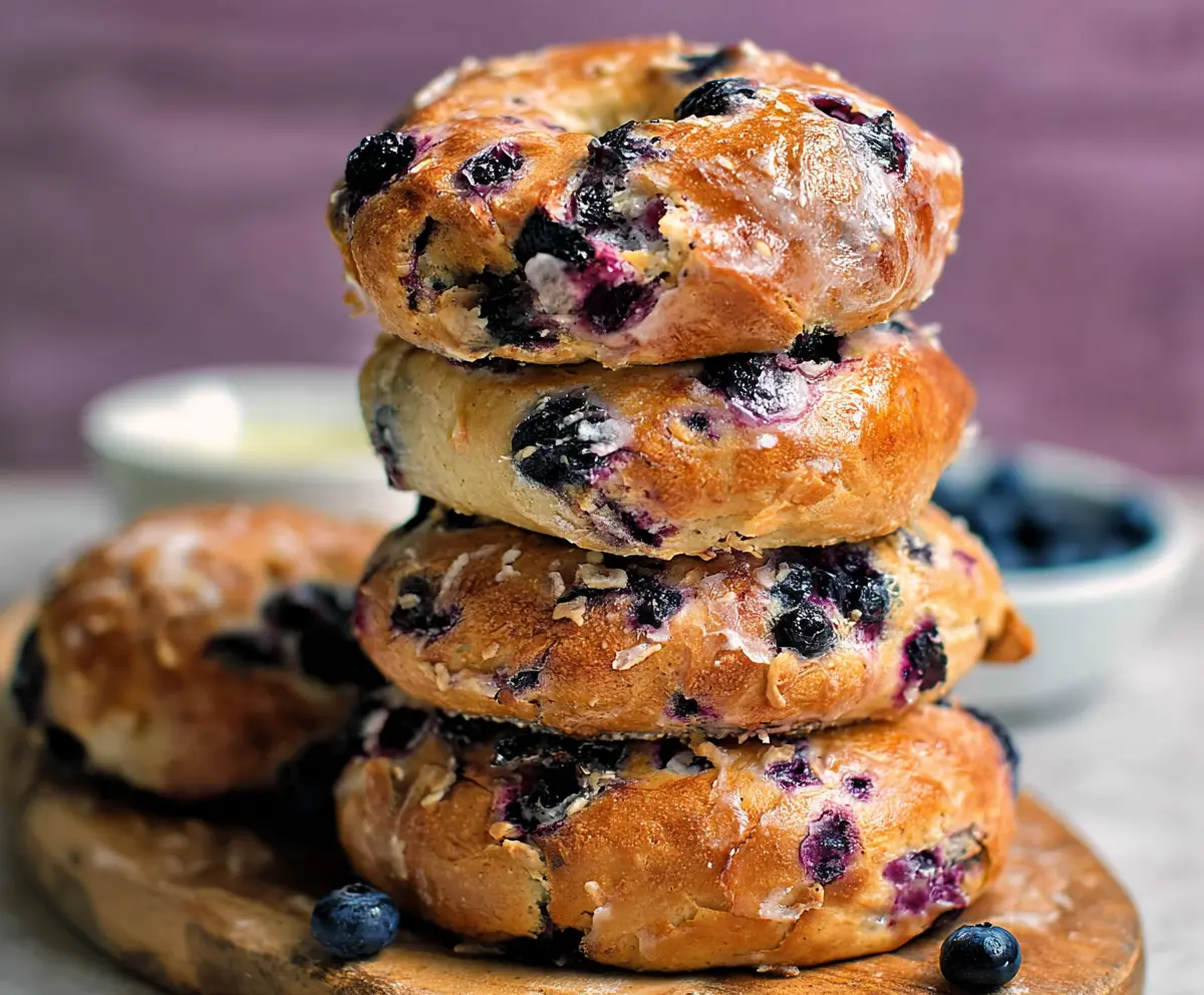 Delicious homemade 4 ingredient blueberry bagels on a baking tray with fresh blueberries.