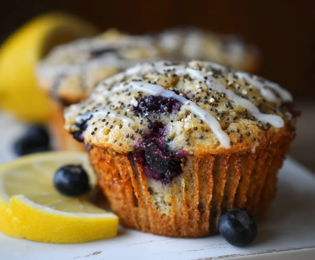 Delicious Blueberry Lemon Poppy Seed Sourdough Muffins on a plate with fresh blueberries and lemon slices