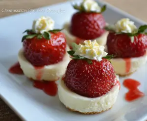 Delicious cheesecake-stuffed deviled strawberries on a white plate, garnished with chocolate drizzle and fresh mint.