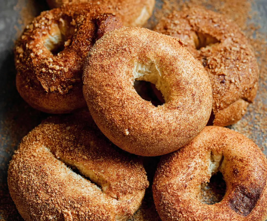 Freshly baked cinnamon bagels with a golden crust and a sprinkle of cinnamon on top.