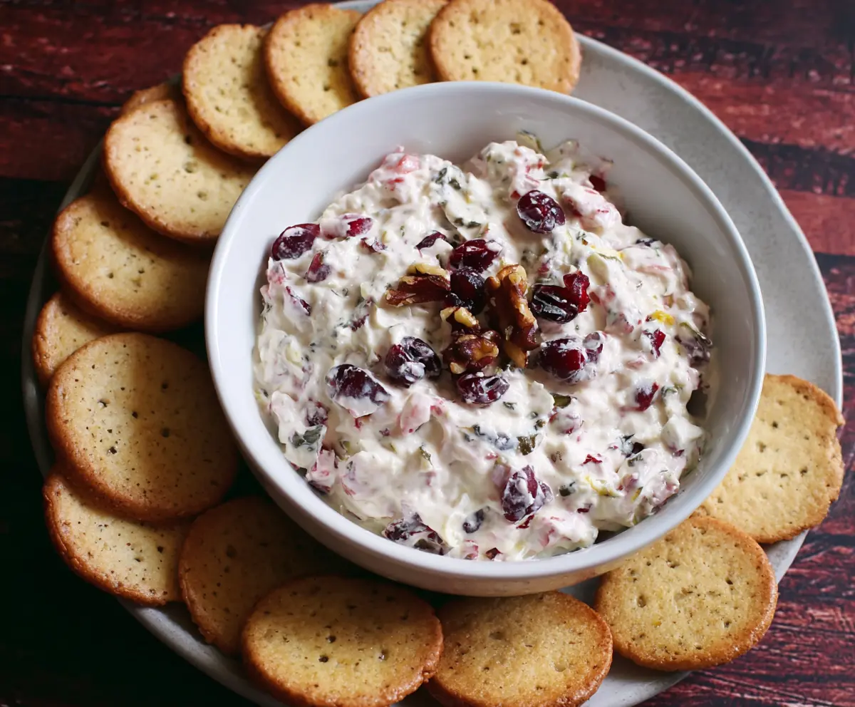 Creamy cranberry walnut dip with cream cheese served in a bowl, perfect for parties.