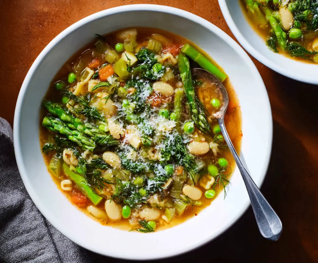 Colorful Spring Minestrone Soup featuring fresh vegetables and herbs in a vibrant bowl.