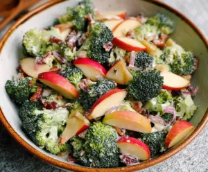 Fresh broccoli and apple salad in a bowl, with vibrant green and red colors, perfect for healthy eating.
