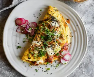 Delicious Everything Bagel Omelet with melted cheese and fresh herbs on a breakfast plate
